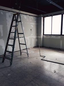 Werker op kamersteiger tijdens renovatiewerkzaamheden met veilige werkomgeving en platform voor gereedschap